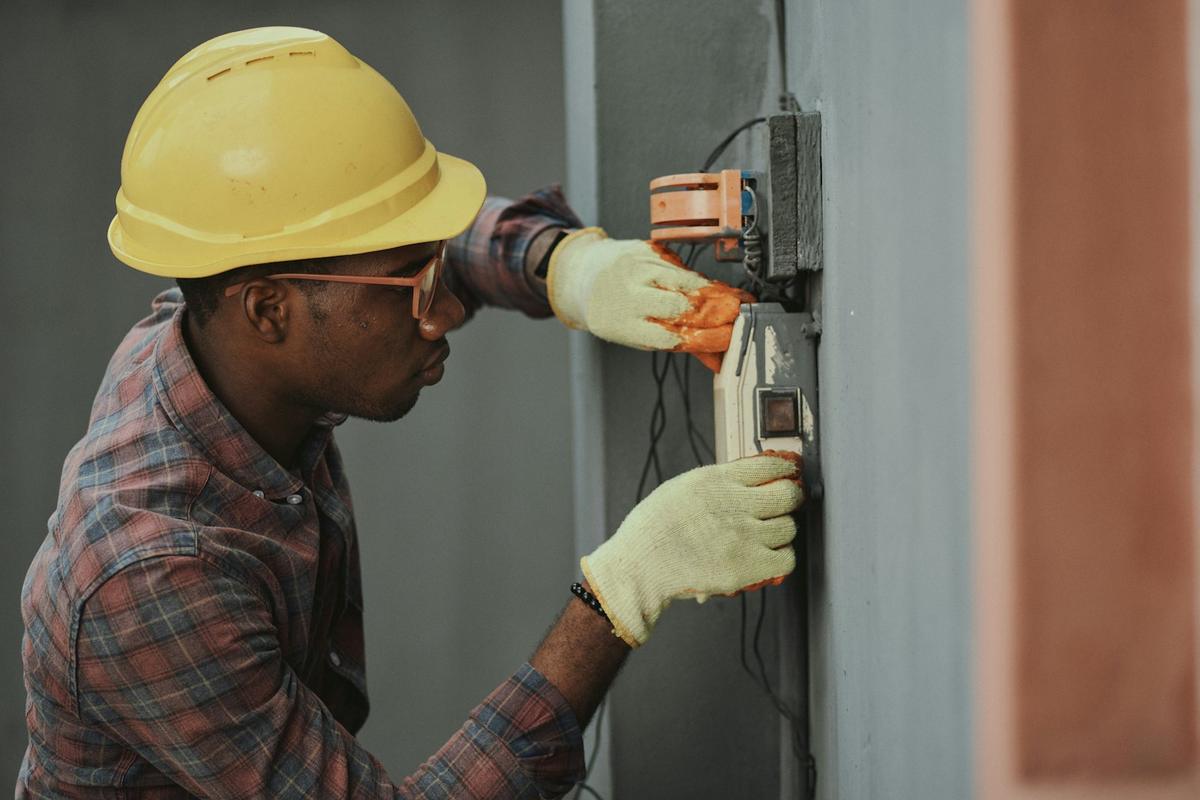 An electrician in a hard hat working on wiring
