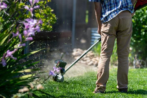 A groundskeeper trimming the edge of a lawn