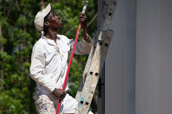 A painter on a ladder painting an outside wall