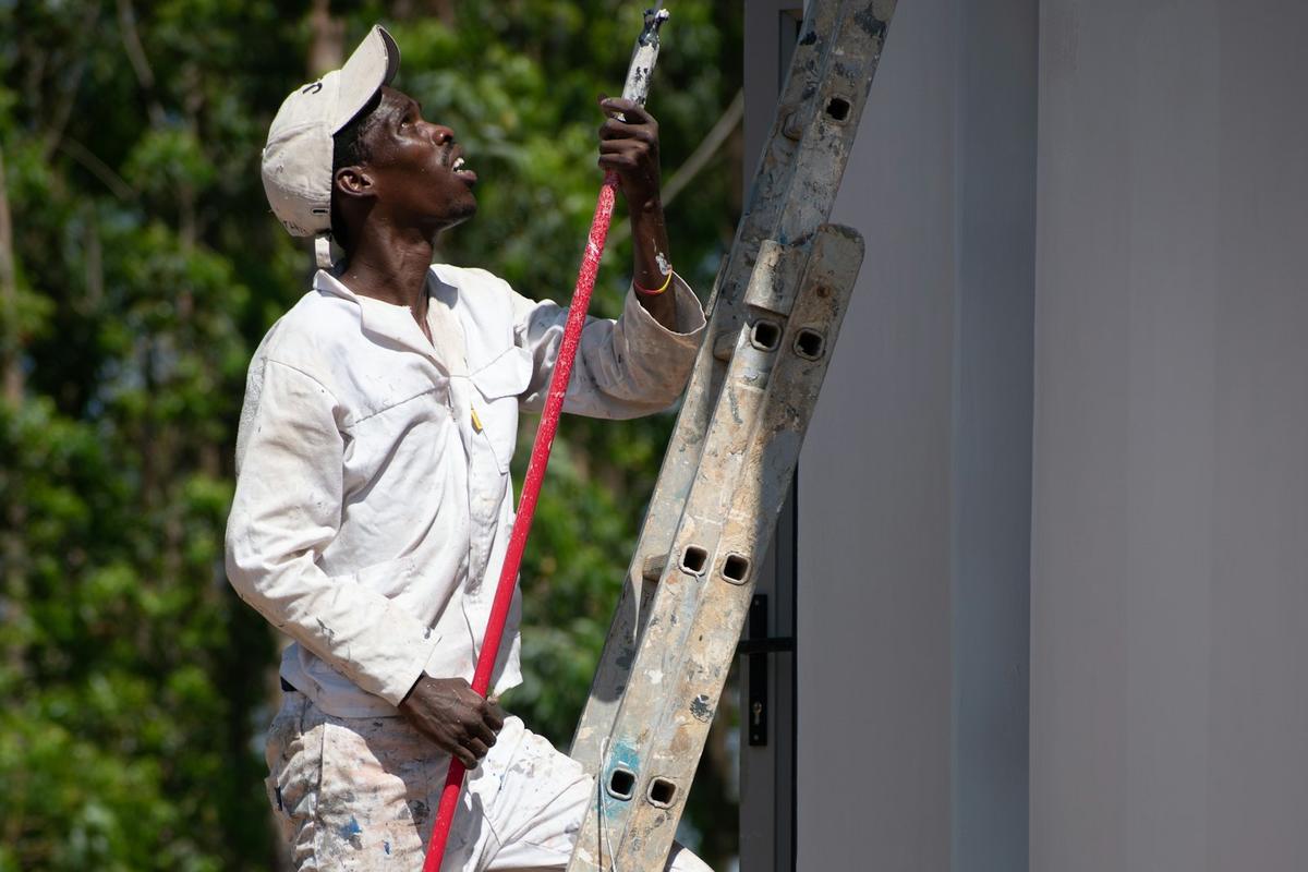 A painter on a ladder painting an outside wall