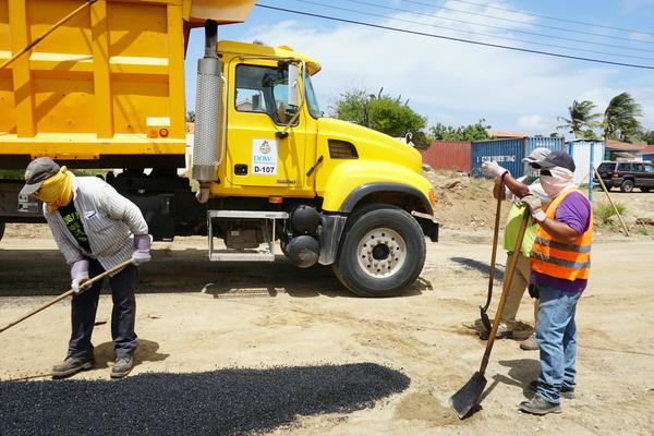 A paving crew spreading asphalt beside a dump truck